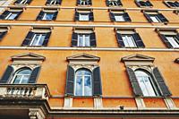 Low angle shot showing details of European classic building with beautiful Italian architectural style window panels located on street of Rome in Ital...