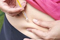 Woman is doing an heparin injection in her abdomen at home.