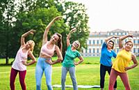 Multiethnic group of senior women training at park with fitness instructor - Active elderly people doing sport in the nature.