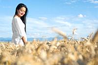 Young Hispanic woman in white dress walking in the middle of a wheat field smiling. High quality photography.