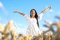 Portrait of happy young woman in a white dress, on a wheat field. Lifestyle and happiness concept. Woman with open arms . High quality photo.