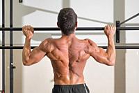 Athlete doing pull-ups at the gym. Handsome man doing functional training. High quality photo.