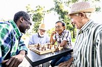 Group of senior friends playing chess game at the park. Lifestyle concepts about seniority and third age.