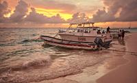 Boats moored on the shore of Isla Mujeres beach at sunset.