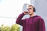Young sports man in hoodie with headphones on work out area.