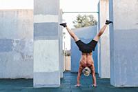 Handstand yoga pose by athlete man on the sport ground outdoors, natural lifestyle photo.