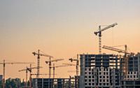 Summer evening at the construction of residential buildings. Lots of cranes are in operation.