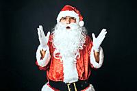 Man dressed as Santa Claus surprised, with raised hands, on black background. Christmas concept, Santa Claus, gifts, celebration.