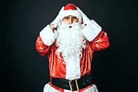 Man dressed as Santa Claus surprised with hands on head, on black background. Christmas concept, Santa Claus, gifts, celebration.