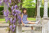 Seven year old girl sitting under a wisteria tree in Honfleur, France.