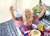 Woman, 70, gestures at dinner, Mayne Island, Gulf Islands, British Columbia, Canada.