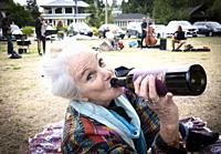 A woman, 70, drinks wine at Locarno Beach, Vancouver, BC, Canada.