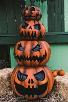 Three decorative Halloween Jack-o-Lantern pumpkins, one on top of the other, on the street. Halloween and carnival celebration concept.