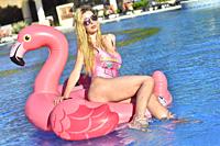 Sexy young blonde girl on the inflatable in the pool.