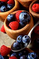Raspberries and blueberries in wooden bowls.