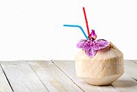 Young coconut with orchid flower on wooden table isolated on white background.