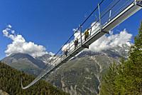 Hikers crossing the Charles Kuonen Suspension Bridge, the longest pedestrian suspension bridge in the Alps, Randa, Valais, Switzerland.
