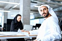 Man and woman with traditional clothes working in a business office of Dubai. Portraits of successful entrepreneurs businessman and businesswoman in f...