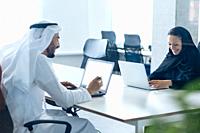 Man and woman with traditional clothes working in a business office of Dubai. Portraits of successful entrepreneurs businessman and businesswoman in f...