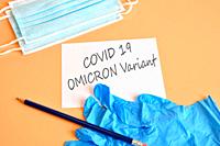 Covid-19 new Omicron variant. Medical face masks, blue medical gloves and pencil with white paper and text ""Covid-19 Variant Omicron"". Concept of pr...