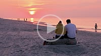 Couple watching sunset over Baltic Sea beach in Debki village, Puck County, Pomerania region of Poland