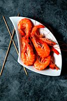 Cooked prawns in a white tray on a gray background.