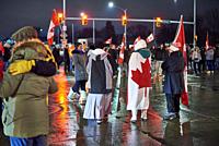 People wear and hold the Canadian flag at an intersection on 11 February 2022, day five, of the Freedom convoy blockade in Windsor, Onrario of the amb...