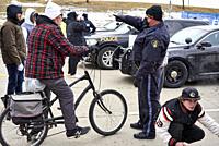 A man on a bike is directed by a police officer to another route to attend the Freedom Convoy blockade of the Ambassador Bridge on 12 February 2022 in...