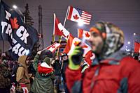 F*ck Trudeau, Canadian and hybrid Canadian United States flags swirl during another rendition of the Canadian national anthem on 11 February 2022 in W...