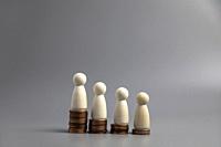 Miniature people standing on piles of different heights of coins. The concepts of person and wealth. investment and teamwork growth copy space.