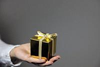 Hands holding gold gift box isolated on gray background. giving present, Birthday,Christmas,Mothersday other Holiday with copy space space for text.