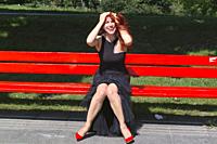 young woman in black on red bench having fun.