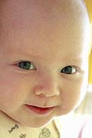 Portrait of smiling baby with blue eyes. Newborn child looking at mother. Face of newborn baby close up.