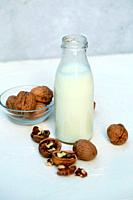 Bottle of nut milk on white wooden board.