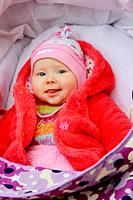 little baby in red suit smiling in perambulator. Happy baby laying in pram. Childish face close up.