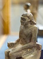Cairo, Egyptian Museum, statuette of Iby, in limestone. He's shown sitted on a chair quite similar to a throne, he wears a wig.