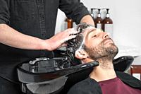 Barber shop. Hairdresser man washes client head in barbershop. High quality photography.