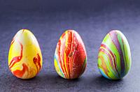Colorful Easter eggs lined up side by side on a trendy black background.