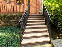 A beautiful staircase with metal railings rises to a red brick building.