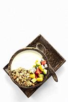 granola muesli healthy breakfast bowl with yogurt and tropical fruit on white background.