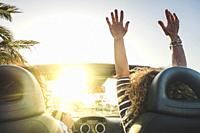 Happy lifestyle women couple enjoy travel with convertible car dancing and driving in the sunset - concept of joyful leisure transport trip activity f...