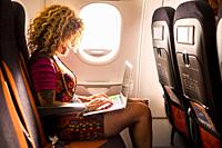 Woman travel on airplane and work with computer laptop and wireless internet connection on beard - people and flight airport activity - modern digital...