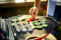 Close up on man's hand roasting vegetables on the barbecue gas grill outdoor in the backyard, Vegetables On Grill, summer family picnic, food on the n...