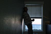 Norfolk, Virginia, USA A man drinks coffee alone in a motel room by the sea.