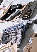 Money and weapons in crime lab for investigation, conceptual image.