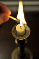 Lighting a candle with a match.