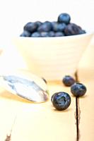 fresh blueberry on a bowl with silver spoon over wood table.