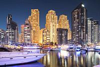 Dubai Marina Port, UAE, United Arab Emirates - Jetty With Many Moored Yachts In Evening Night Illuminations. Night View Of Dubai Marina Towers.