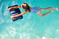 Happy little girl having fun in the swimming pool, dives and swim, summer vacation at home, tropical holiday resort.