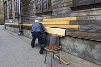 Riga, Latvia, A man uses planks to fix the siding on a house.